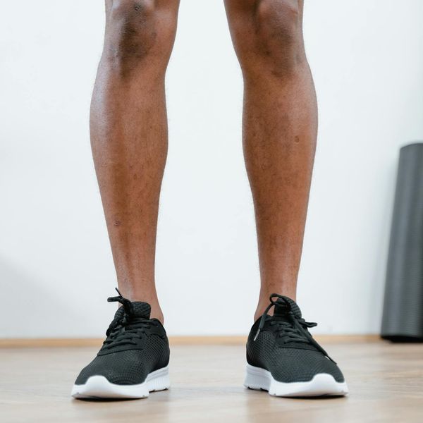 Close-up of a person tying their running shoes on a wooden floor.